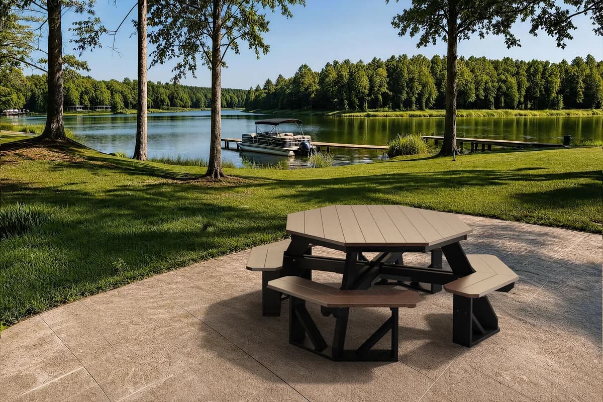 Weathered wood and black Wildridge poly octagon picnic table on a lakeside patio with a pontoon boat docked in the background